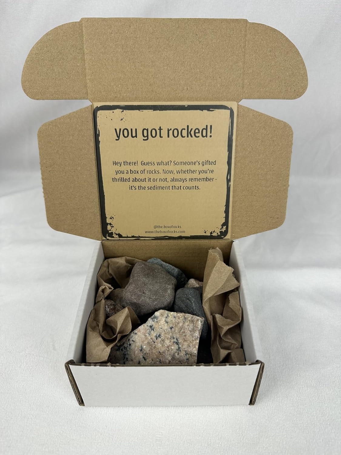 The Box of Rocks open product box with river rocks and insert card